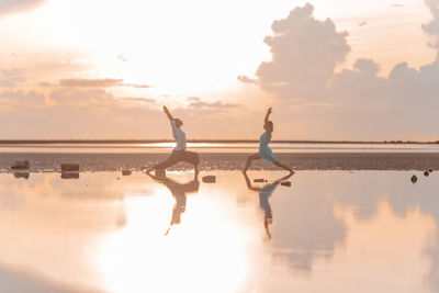 Man and woman doing yoga against the backdrop of the sunrise