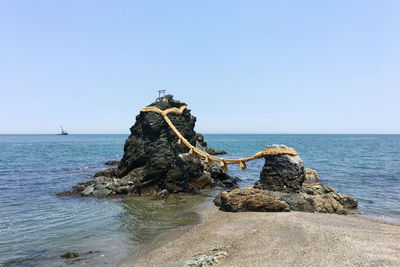 Rock formation on beach against clear sky