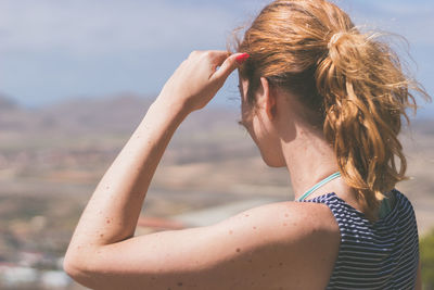 Rear view of woman standing at beach against sky