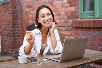 Young businesswoman using laptop while sitting on table