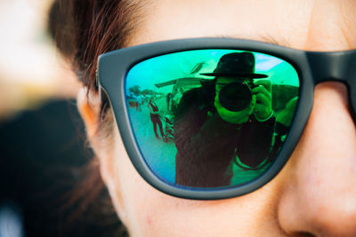 Cropped image of woman with photographer reflecting on sunglasses