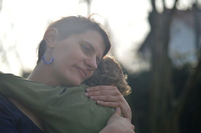 Happy mother holding little child in her arms with love in a garden outdoors in summertime