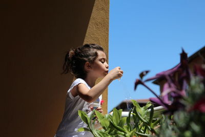 Portrait of girl looking up against clear sky