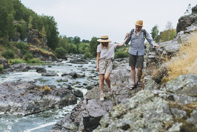 People standing on rock by water