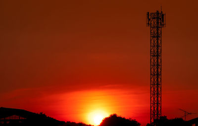 Low angle view of silhouette crane against orange sky