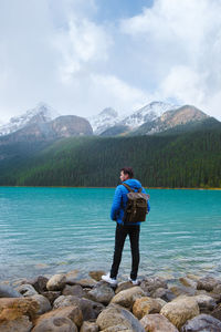 Rear view of man standing by lake