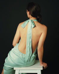 Rear view of woman holding book against black background