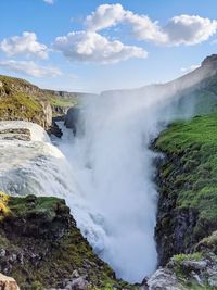 Scenic view of waterfall against sky