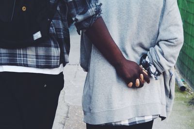 Midsection of interracial couple holding hands on street