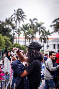 Rear view of people photographing against trees