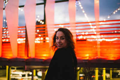 Portrait of smiling young woman standing at night