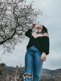 Attractive young beautiful lady happy enjoying the blossoms of the almond tree in spring. 