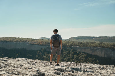 Rear view of man looking at mountains against sky