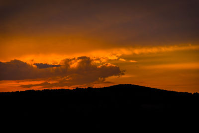 Silhouette landscape against dramatic sky during sunset