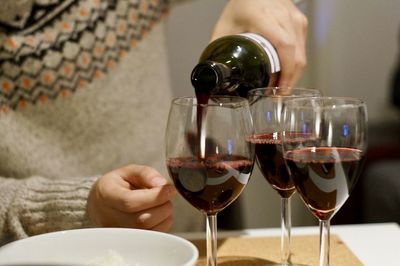 Midsection of man holding wine glass on table