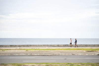 Men by sea against sky