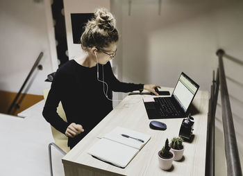 Woman using mobile phone while sitting on table