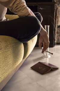 Midsection of man reading book at home