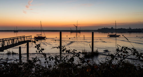 Silhouette sailboats in sea against sky during sunset