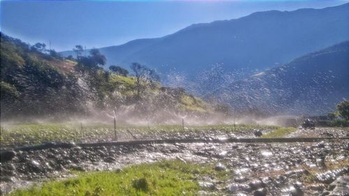 Water splashing on mountain against sky