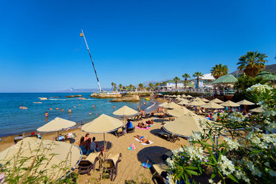 People on beach against clear blue sky