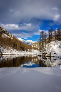 Scenic view of lake by snowcapped mountains against sky