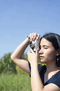 Close-up of woman photographing with camera against clear sky