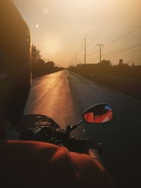 Man riding car on road against sky during sunset