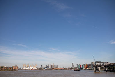 Sea by buildings against blue sky