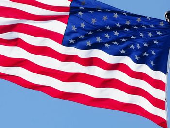 Low angle view of american flag against clear blue sky