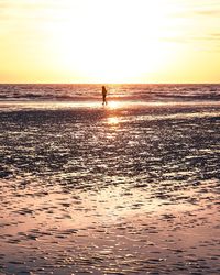 Silhouette man on beach against sky during sunset