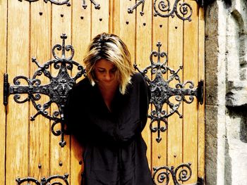 Portrait of young woman standing against closed door