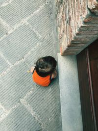 High angle view of boy crouching on footpath