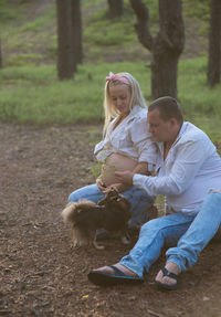 Man sitting by pregnant woman with chihuahua at park