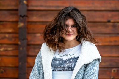 Portrait of young woman standing against brick wall