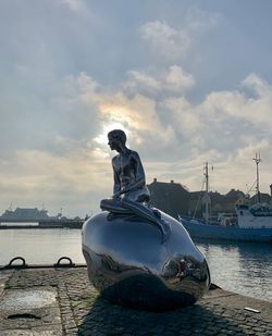 Sculpture by sea against sky during sunset