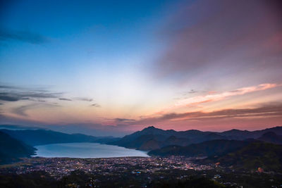 Scenic view of sea and mountains against sky at sunset