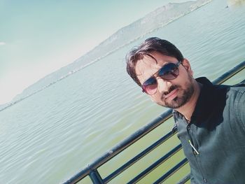 Portrait of young man wearing sunglasses opposit  a lake.