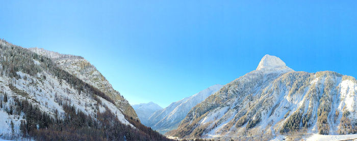 Panoramic view of snowcapped mountains against clear blue sky