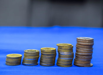 Close-up of coins arranged on blue table