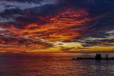 Scenic view of sea against dramatic sky during sunset