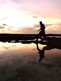 Silhouette man on beach against sky during sunset