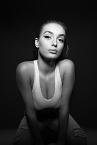 Portrait of woman sitting against black background