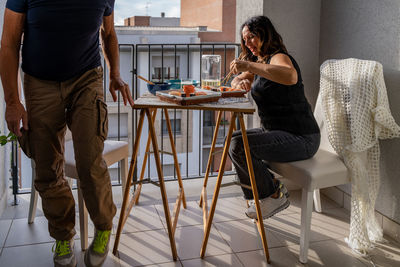 Beautiful middle aged couple eating chinese take away food sitting at a laid table in a city balcony