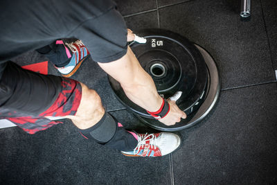 From above of unrecognizable male weightlifter preparing weights for training in modern sports club