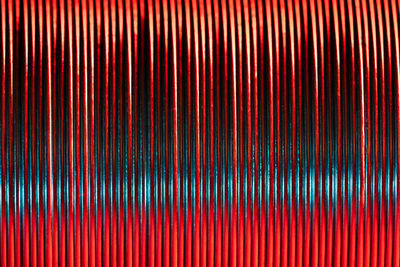 Closeup of coiled metal spring rings in a compressed state in red and blue neon light, macro shot