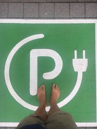 Low section of man standing on footpath sign