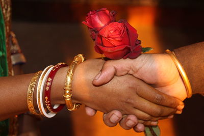 Cropped image of couple holding hands with roses