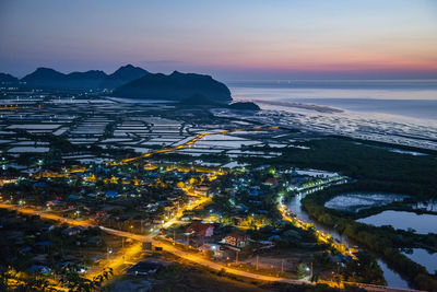 Aerial view of illuminated cityscape against sky during sunset