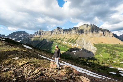 Woman standing on land against cloudy sky